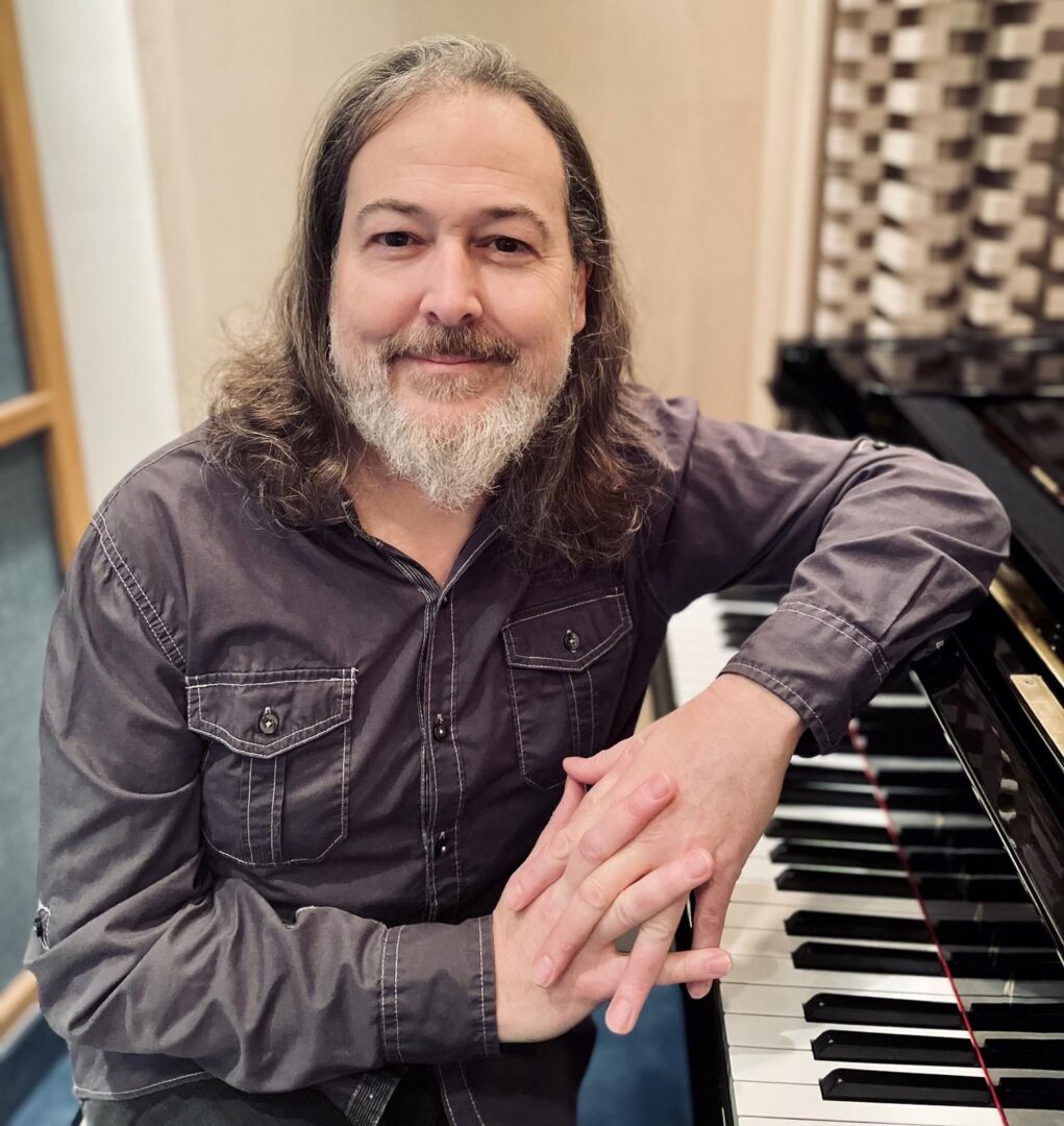 Man with beard sitting at piano.