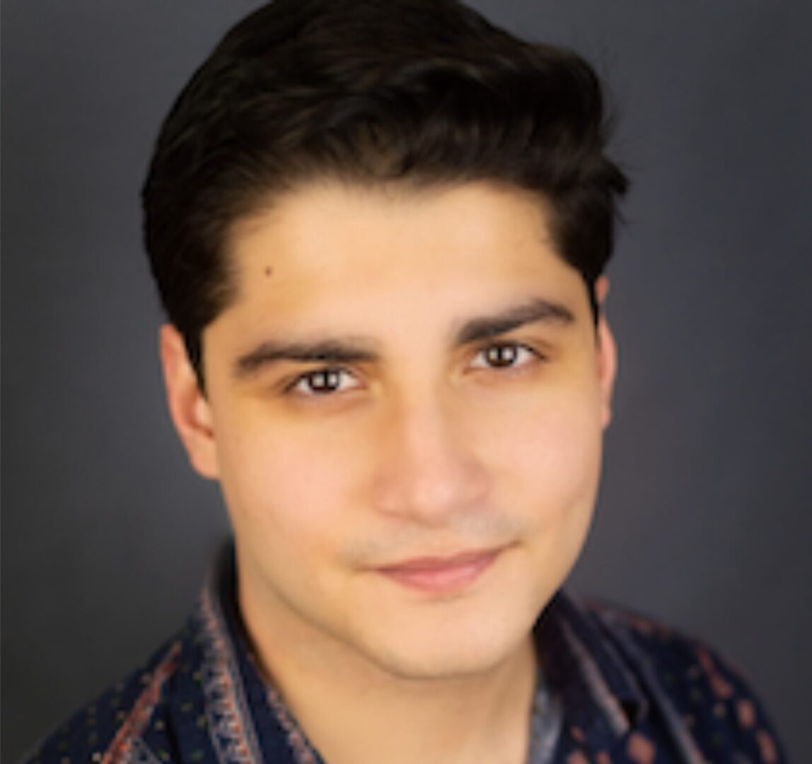 A young man with dark hair and a blue shirt.