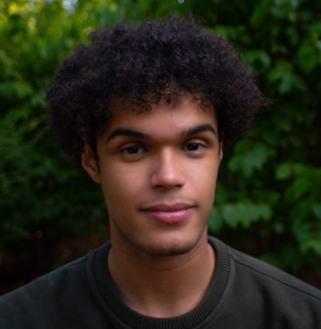 Young man with curly hair looking at camera.