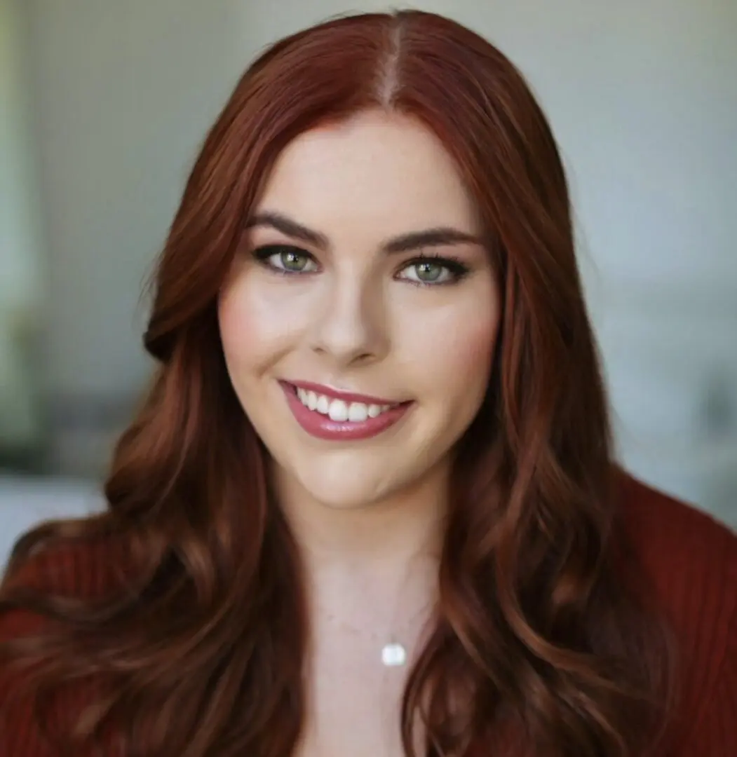 Woman with long red hair smiling.