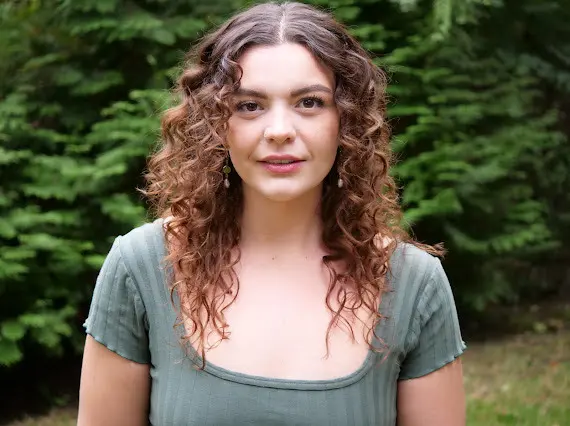 Woman with curly hair wearing a green shirt.